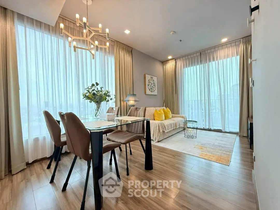 Spacious modern living room with elegant dining area and large windows offering city views.