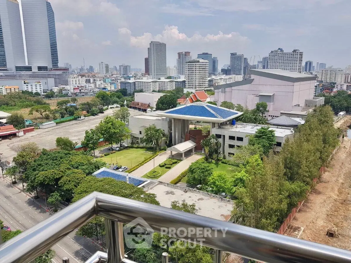 Stunning cityscape view from a balcony overlooking modern architecture and lush greenery.