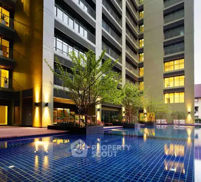 Luxurious apartment building with illuminated pool and modern exterior design.