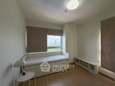 Bright bedroom with large window and minimalist furniture, offering a serene city view.