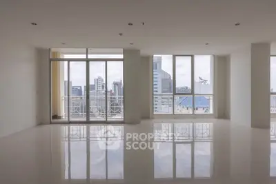 Spacious modern living room with city view and large windows in high-rise apartment.