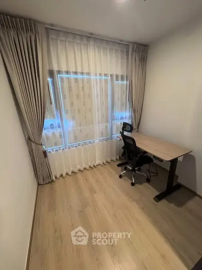 Modern study room with sleek desk and ergonomic chair, featuring elegant curtains and wooden flooring.