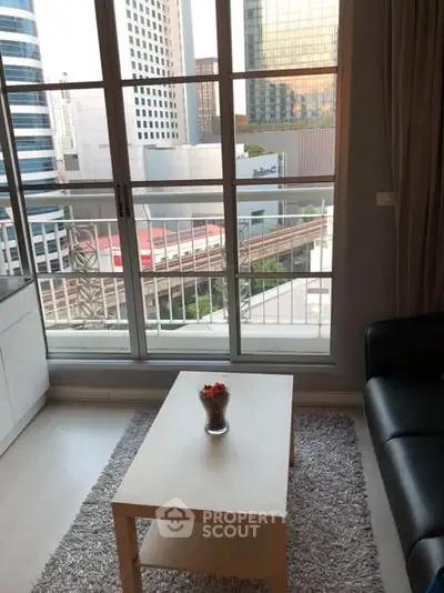 Modern living room with city view and balcony access in high-rise apartment.