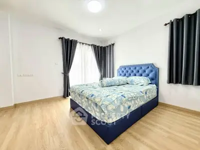 Spacious bedroom with elegant blue bed and natural light from large windows.