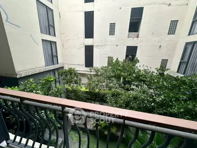 Charming balcony view overlooking lush garden in modern apartment complex.