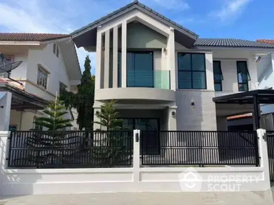 Modern two-story house with sleek design and large windows in a suburban neighborhood.