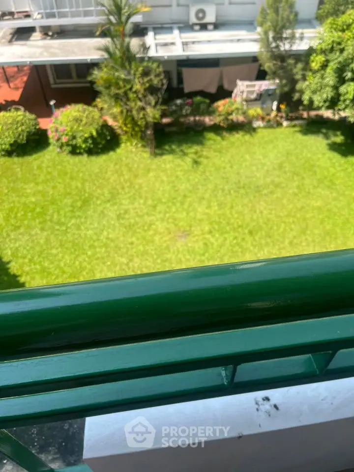 Lush green garden view from a balcony in a modern residential complex.