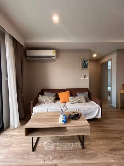 Modern living room with stylish decor and natural light, featuring a cozy sofa and sleek wooden coffee table.