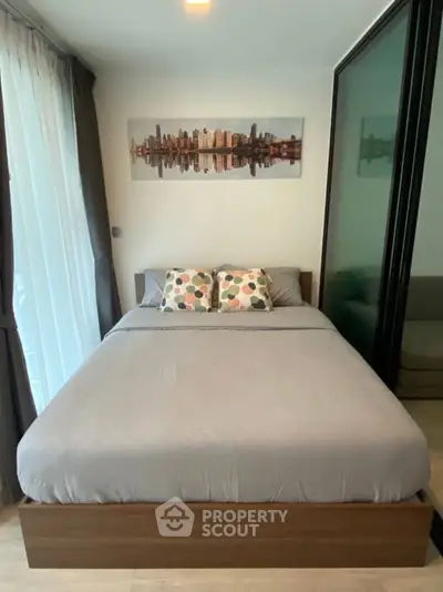 Modern bedroom with cityscape artwork and cozy bedding in a stylish apartment.