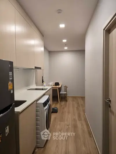 Modern kitchen with sleek cabinetry and integrated washing machine in a compact layout.