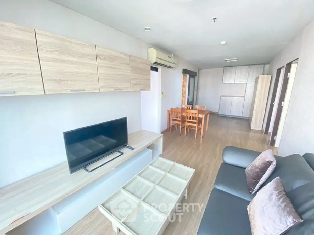 Spacious living room with modern furniture and dining area in open layout apartment.