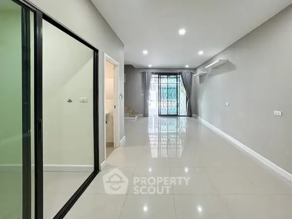 Spacious modern living room with large windows and sleek tile flooring.