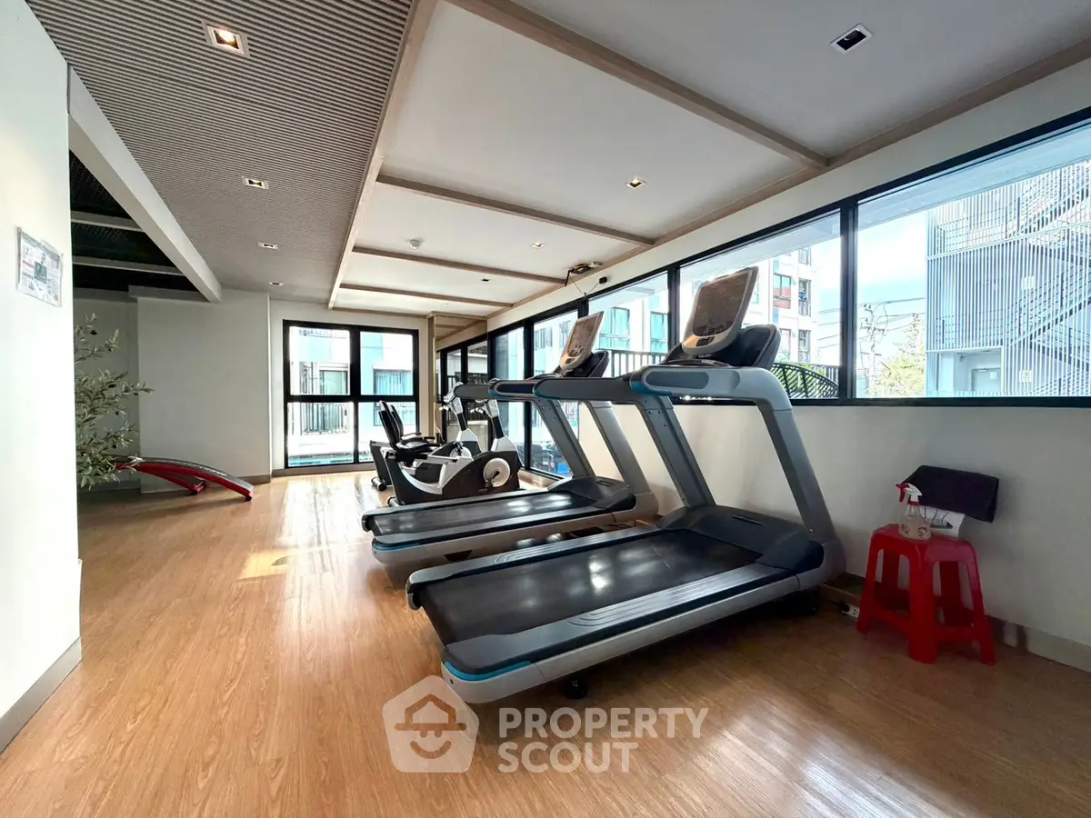 Modern gym with treadmills and exercise equipment in a bright, spacious room with large windows.