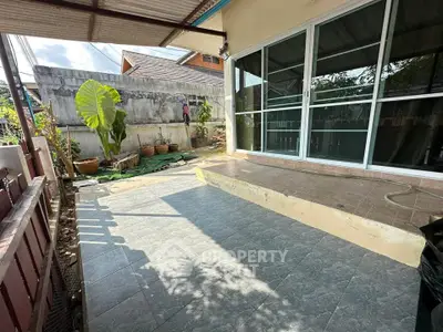 Charming patio with sliding glass doors and garden view, perfect for outdoor relaxation.