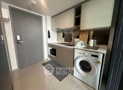 Modern compact kitchen with washing machine and sleek cabinetry in a stylish apartment.