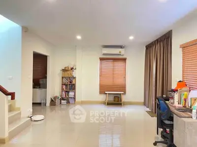 Spacious living room with modern decor and natural light, featuring a study area and air conditioning.
