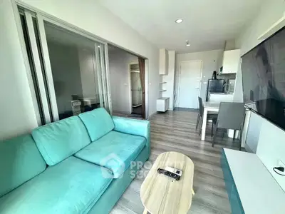 Modern living room with teal sofa and sleek dining area in open layout apartment.