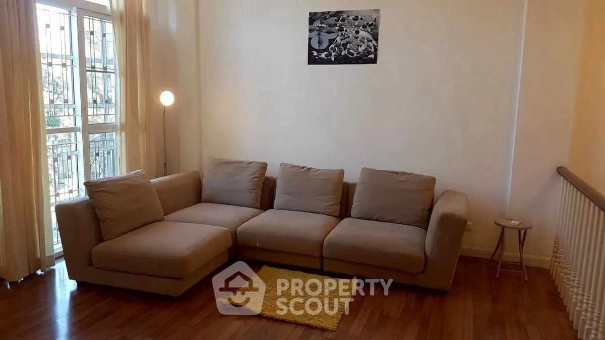 Spacious living room with cozy sectional sofa and natural light from large windows.