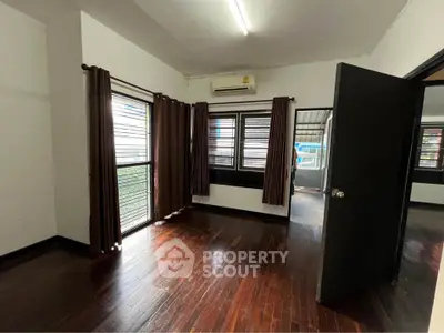Spacious room with wooden flooring and large windows, perfect for natural light and comfort.