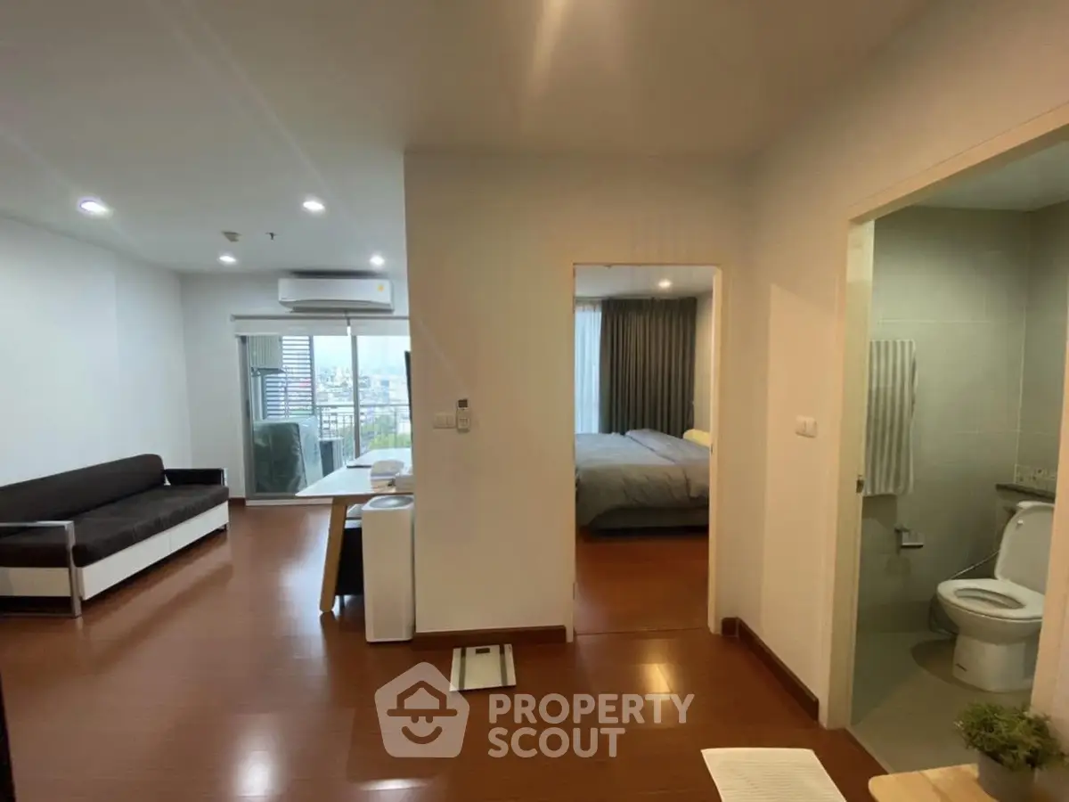 Modern apartment interior with living room, bedroom, and bathroom, featuring wooden flooring and city view.