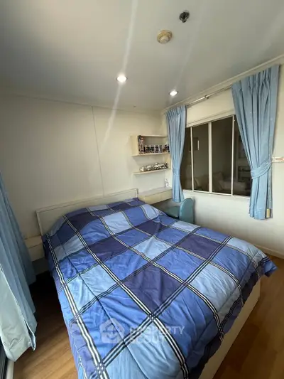 Cozy bedroom with blue decor and natural light in modern apartment.