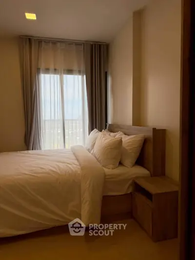 Cozy bedroom with modern decor and large window offering natural light.