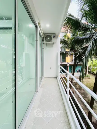 Spacious balcony with lush garden view and modern glass railing.