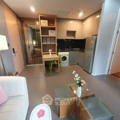 Modern apartment interior with open kitchen, washing machine, and cozy living area.