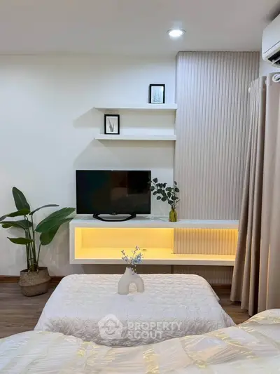 Modern bedroom with stylish decor, wall-mounted TV, and cozy lighting for a serene ambiance.