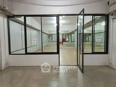Spacious commercial space with glass partitions and open layout, ideal for offices or retail.
