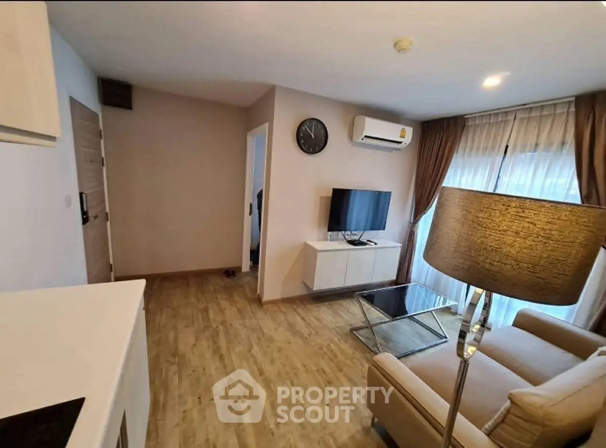 Modern living room with wooden flooring, cozy sofa, and wall-mounted TV in a stylish apartment.