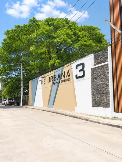 Modern residential building entrance with stylish design and lush greenery.