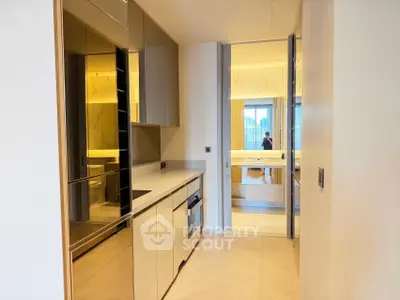 Modern kitchen with sleek cabinetry and open layout leading to a bright bathroom.