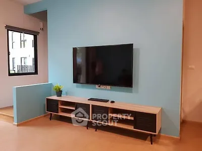 Modern living room with wall-mounted TV and stylish console in bright interior.