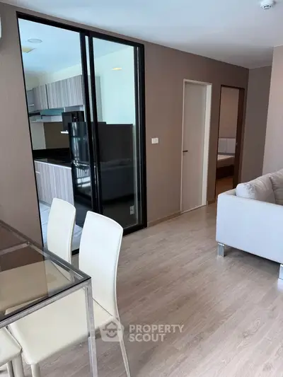 Modern open-plan living room with sleek kitchen and dining area, featuring light wood flooring and contemporary furniture.