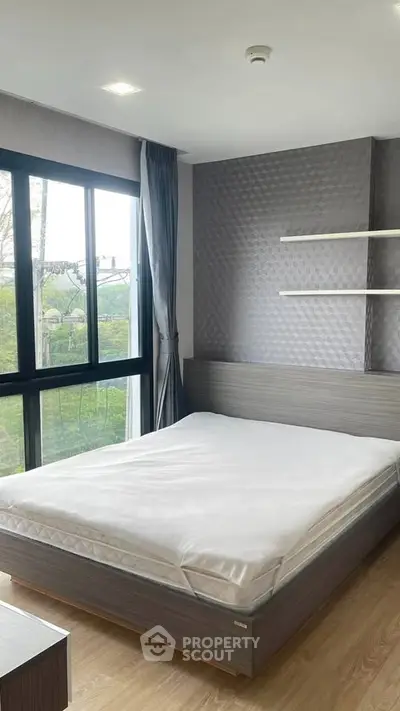 Modern bedroom with large window and stylish decor in a contemporary apartment.