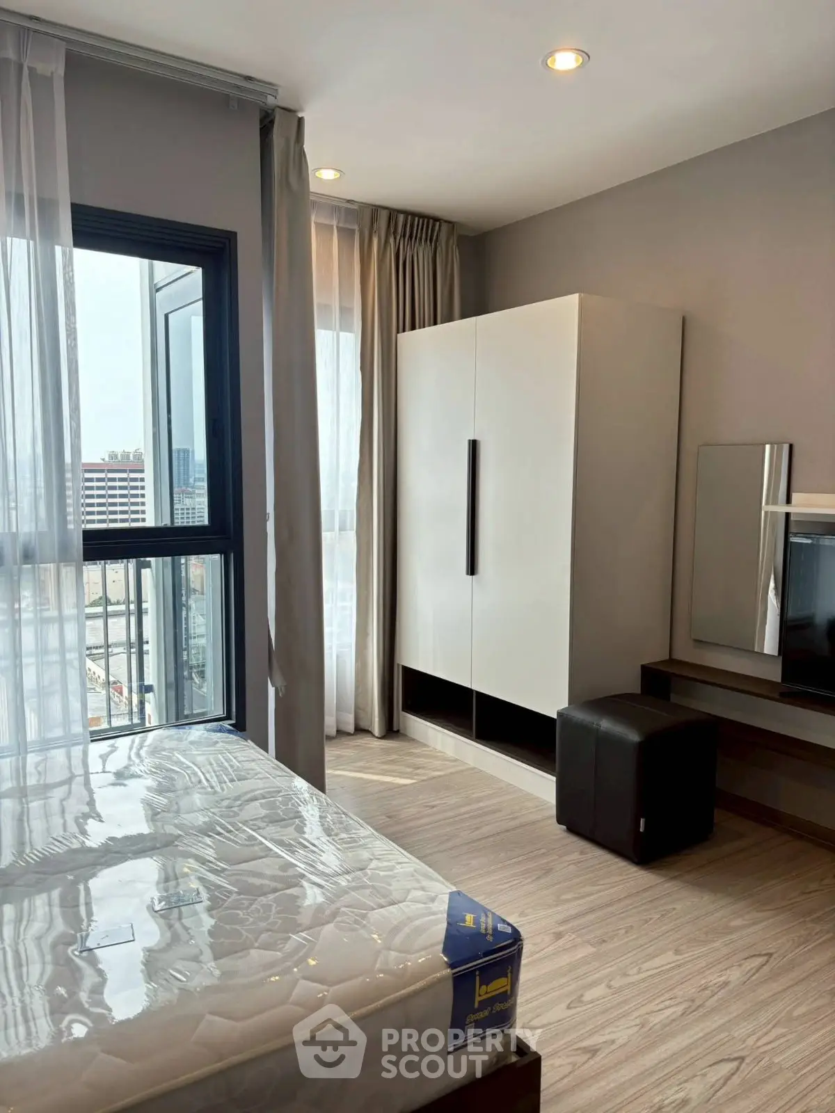 Modern bedroom with large window and stylish furniture in urban apartment