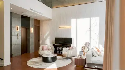 Luxurious living room with high ceiling, elegant decor, and natural light