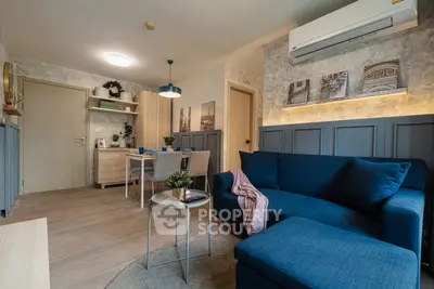 Stylish living room with modern blue sofa and dining area in open layout apartment.