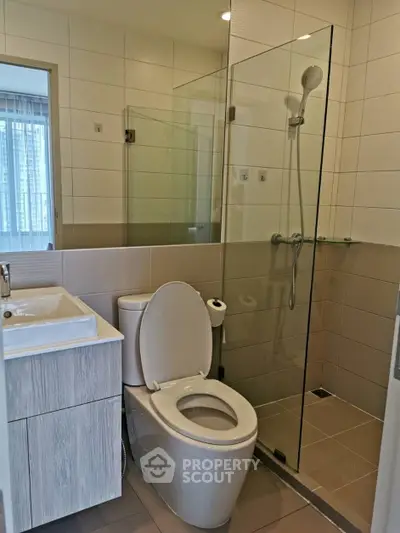 Modern bathroom with glass shower and sleek vanity in contemporary apartment.