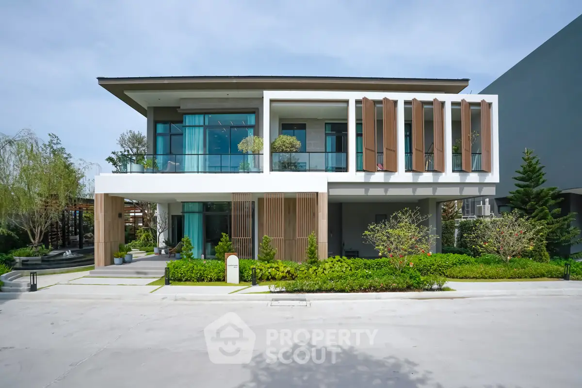 Modern two-story house with large windows and lush garden