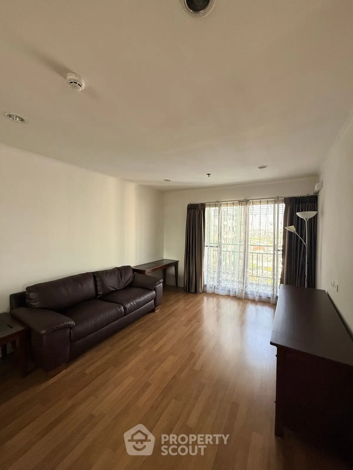 Spacious living room with wooden flooring and large window for natural light.