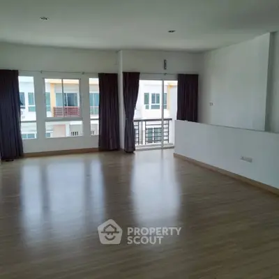 Spacious and bright living room with large windows and balcony access in modern apartment.