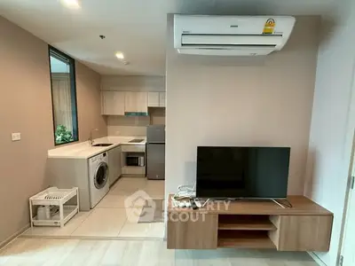 Modern apartment interior with kitchen and living area featuring washing machine and TV setup.