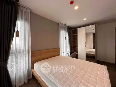 Modern bedroom with large windows and stylish wooden furniture in a contemporary apartment.