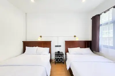 Bright bedroom with two beds and modern lighting, perfect for a cozy stay.