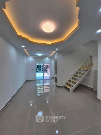 Spacious modern living room with elegant ceiling lights and sleek staircase