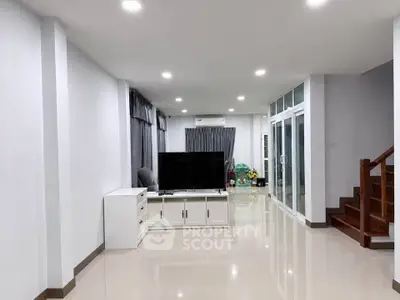 Spacious modern living room with sleek design and large TV setup, perfect for relaxation and entertainment.