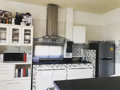 Modern kitchen with sleek appliances and stylish backsplash, featuring a microwave and refrigerator.