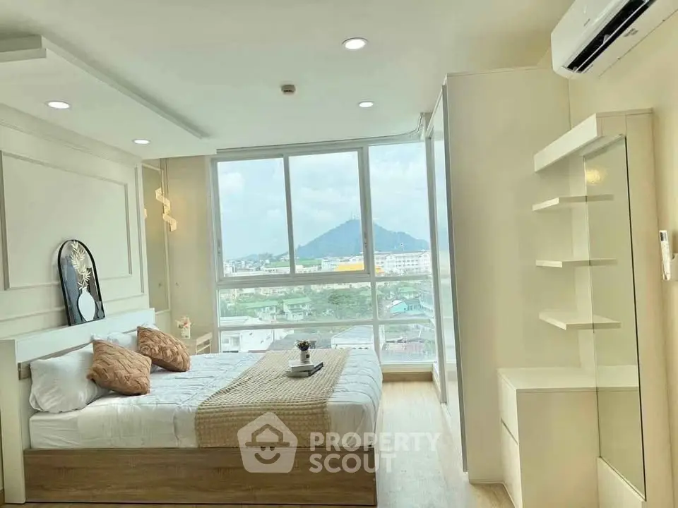 Bright and airy bedroom with large windows offering stunning mountain views, modern decor, and ample storage.